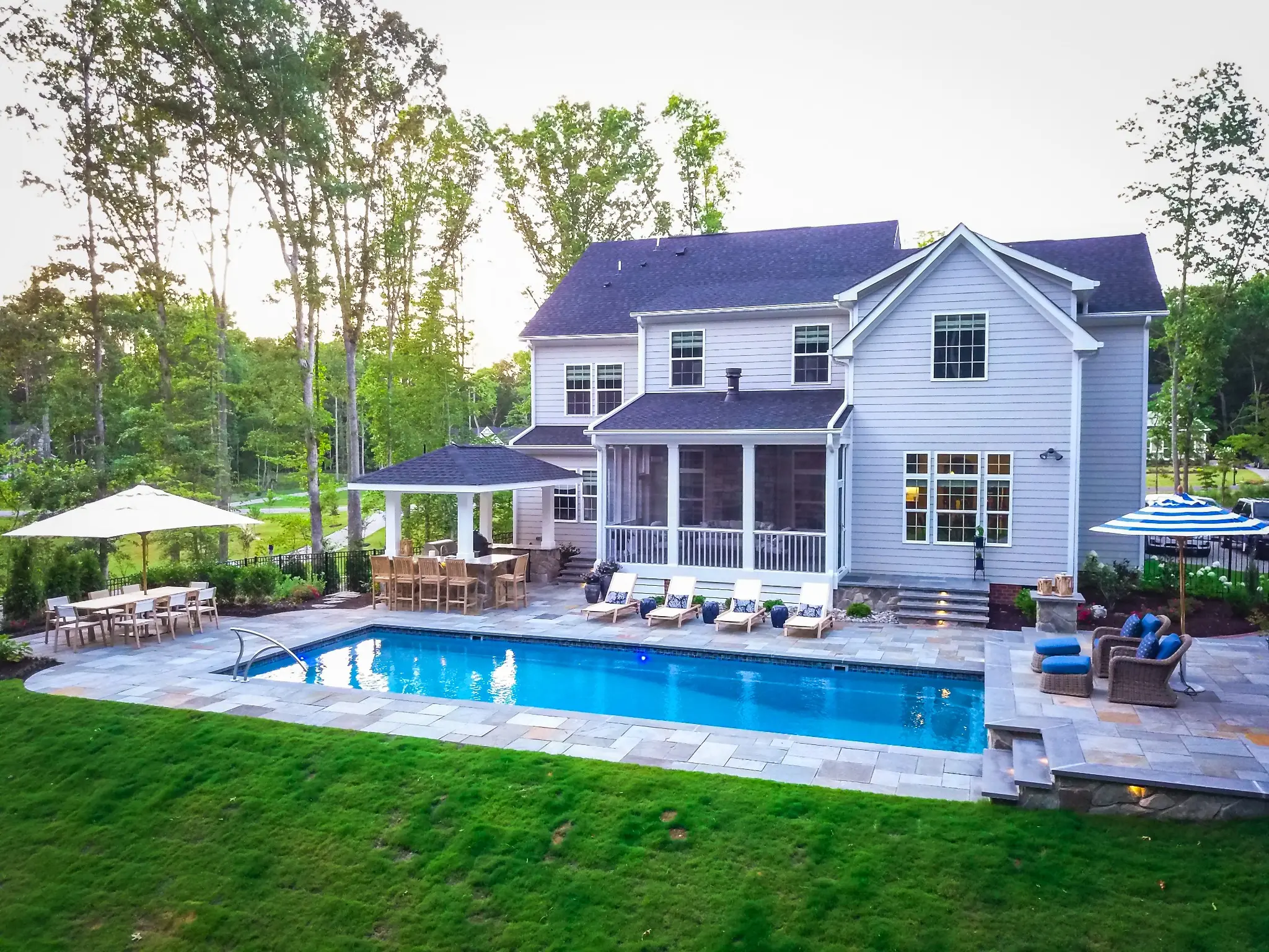 Complete backyard with rectangular pool, paver patio, outdoor kitchen pavilion, dining, lounge seating, and landscape